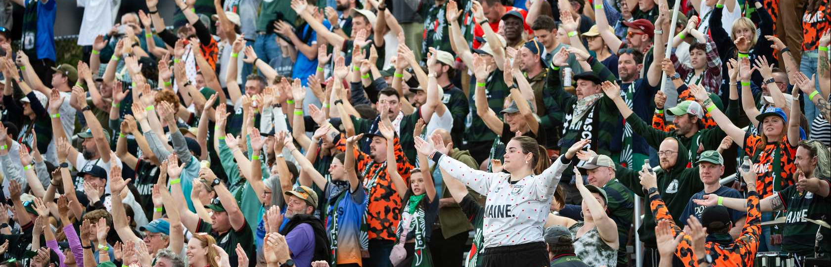 Crowd of people with raised hands in a celebratory manner outdoors