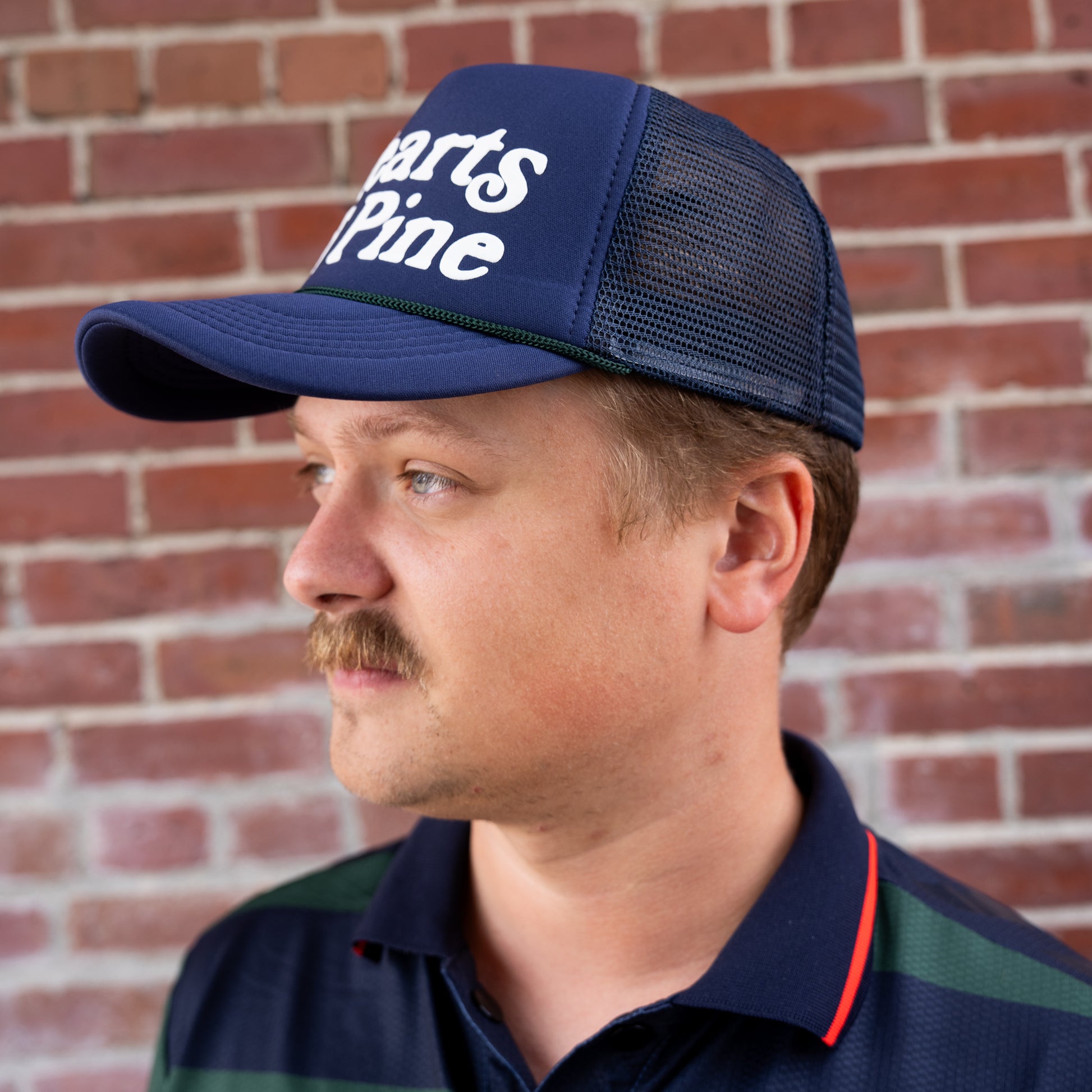 Man wearing a blue cap with text against a brick wall