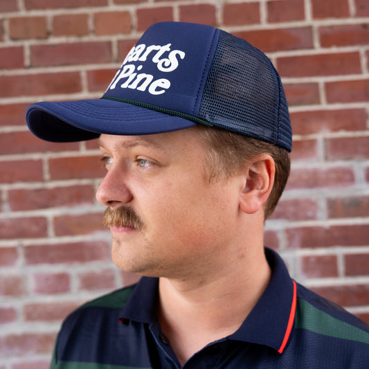 Man wearing a blue cap with text against a brick wall