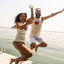 Two people jumping off a dock with heart designs on their shirts.